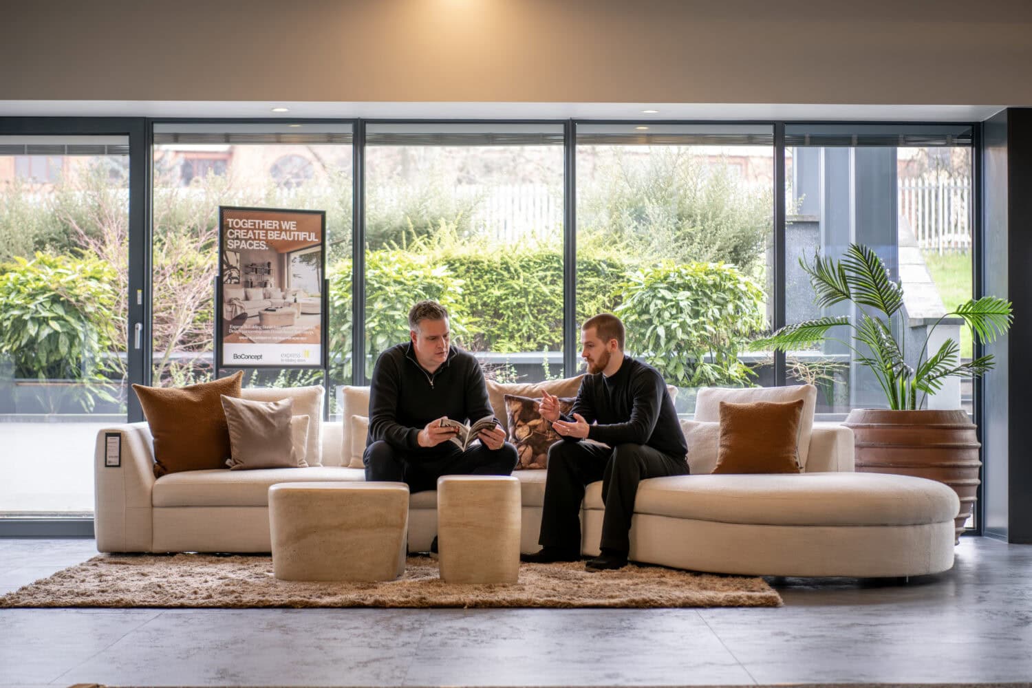 Elegant bi-folding doors opening to a bright, modern lounge with comfortable seating and lush greenery outside.