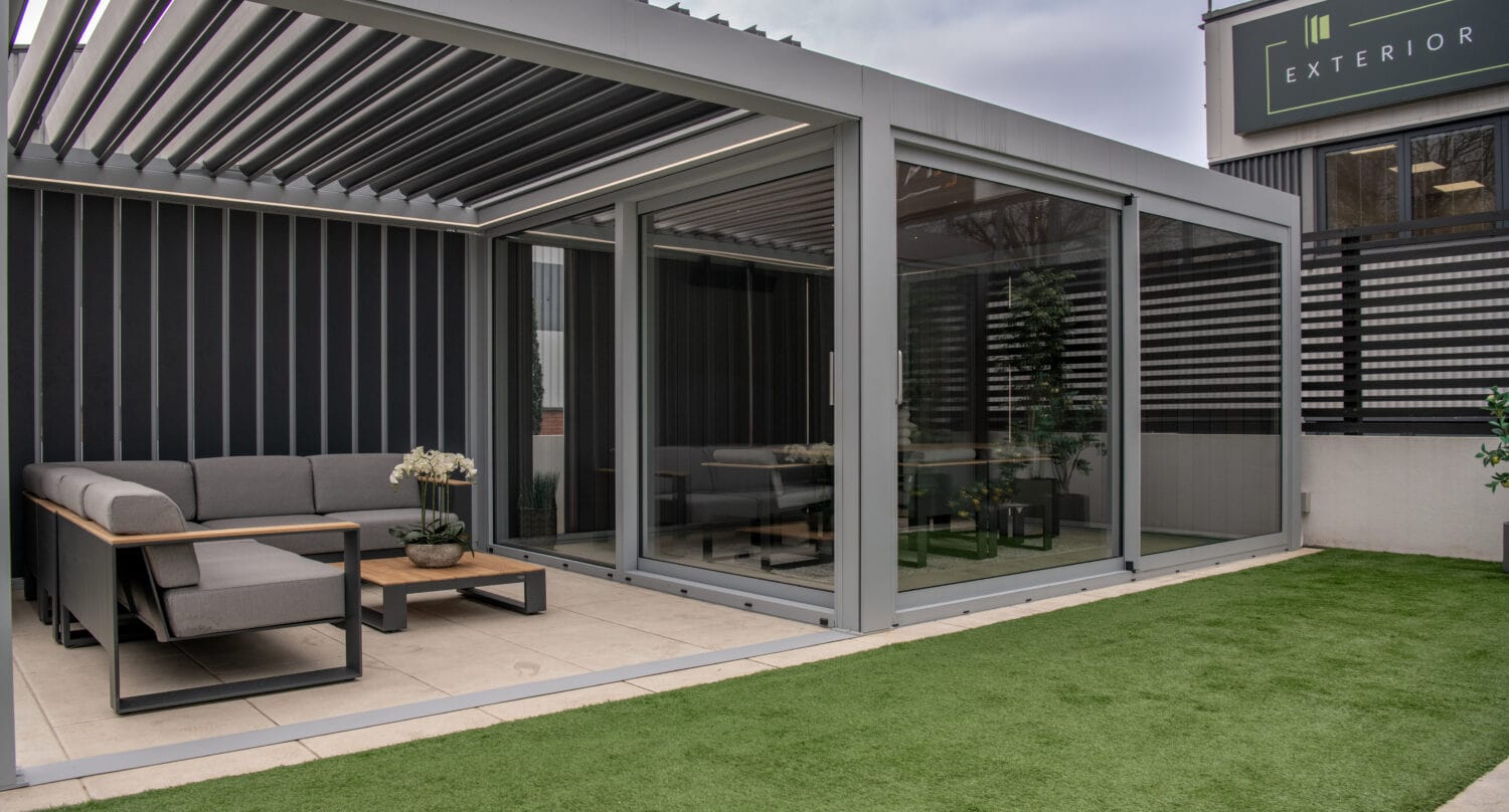 Aluminium bi-fold doors opening to a stylish outdoor patio area, providing seamless indoor-outdoor living space with large glass panels and sleek grey frames.