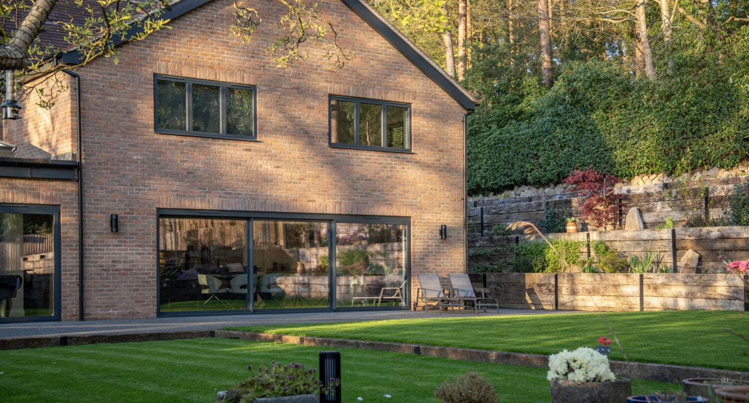 Contemporary brick house featuring large bi-folding doors opening to a landscaped garden, ideal for enhancing indoor-outdoor living spaces.