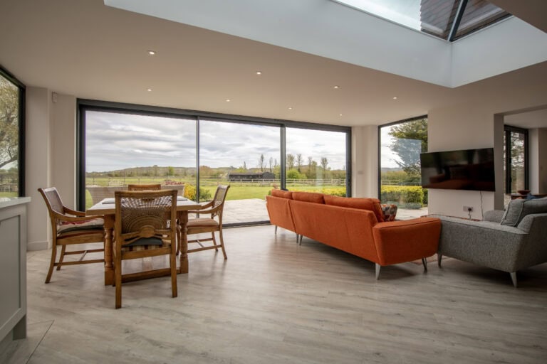 Large glass sliding bi-fold doors opening to a garden, providing natural light and seamless indoor-outdoor living. Perfect for contemporary home designs.