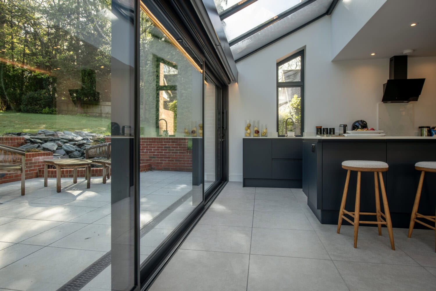 Elegant black bi-folding doors opening to a spacious patio, enhancing natural light and outdoor views. Perfect for stylish, functional home improvements.