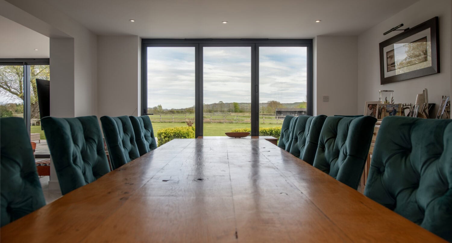 Elegant bi-folding doors opening to a scenic outdoor view, enhancing natural light and space in a contemporary dining area. Perfect for stylish home renovations and outdoor access.