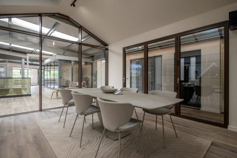 Modern bi-folding doors in a stylish showroom, showcasing seamless indoor-outdoor transition with large glass panels and sleek frames.