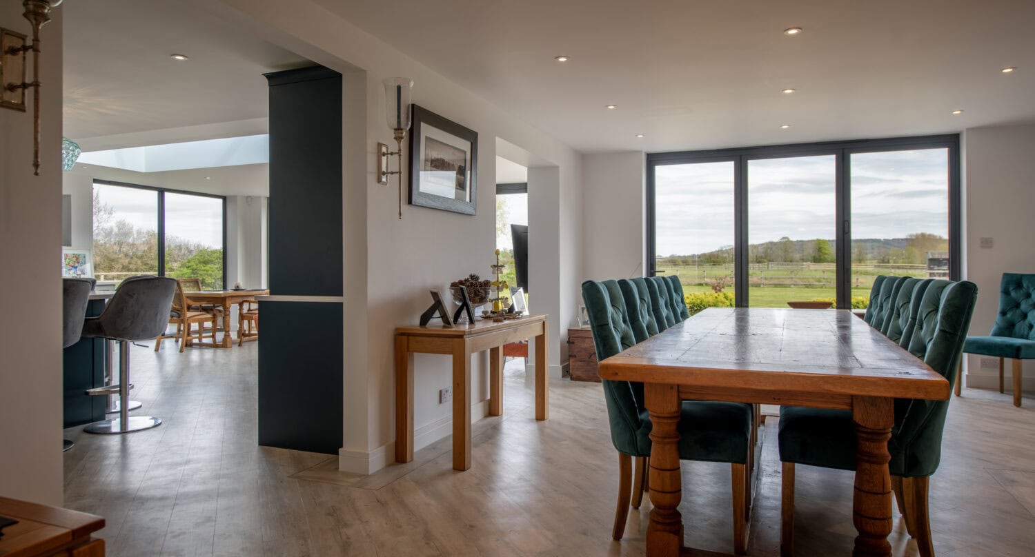 Modern interior with large glass bi-folding doors opening to a scenic outdoor view, showcasing stylish home design and natural light.