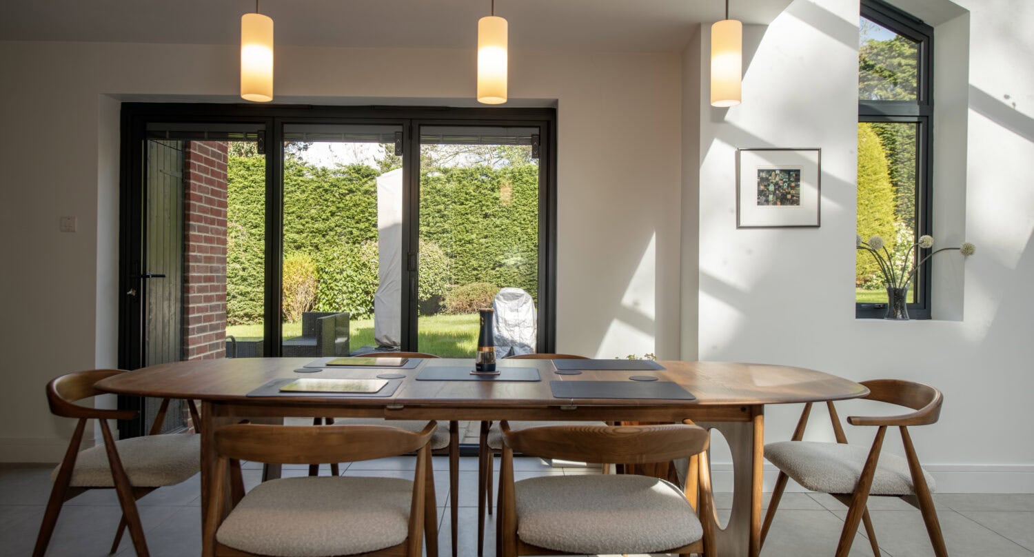 Elegant black bi-fold doors opening to a lush garden, providing natural light and seamless indoor-outdoor living. Perfect for contemporary homes seeking stylish, functional access to outdoor spaces.