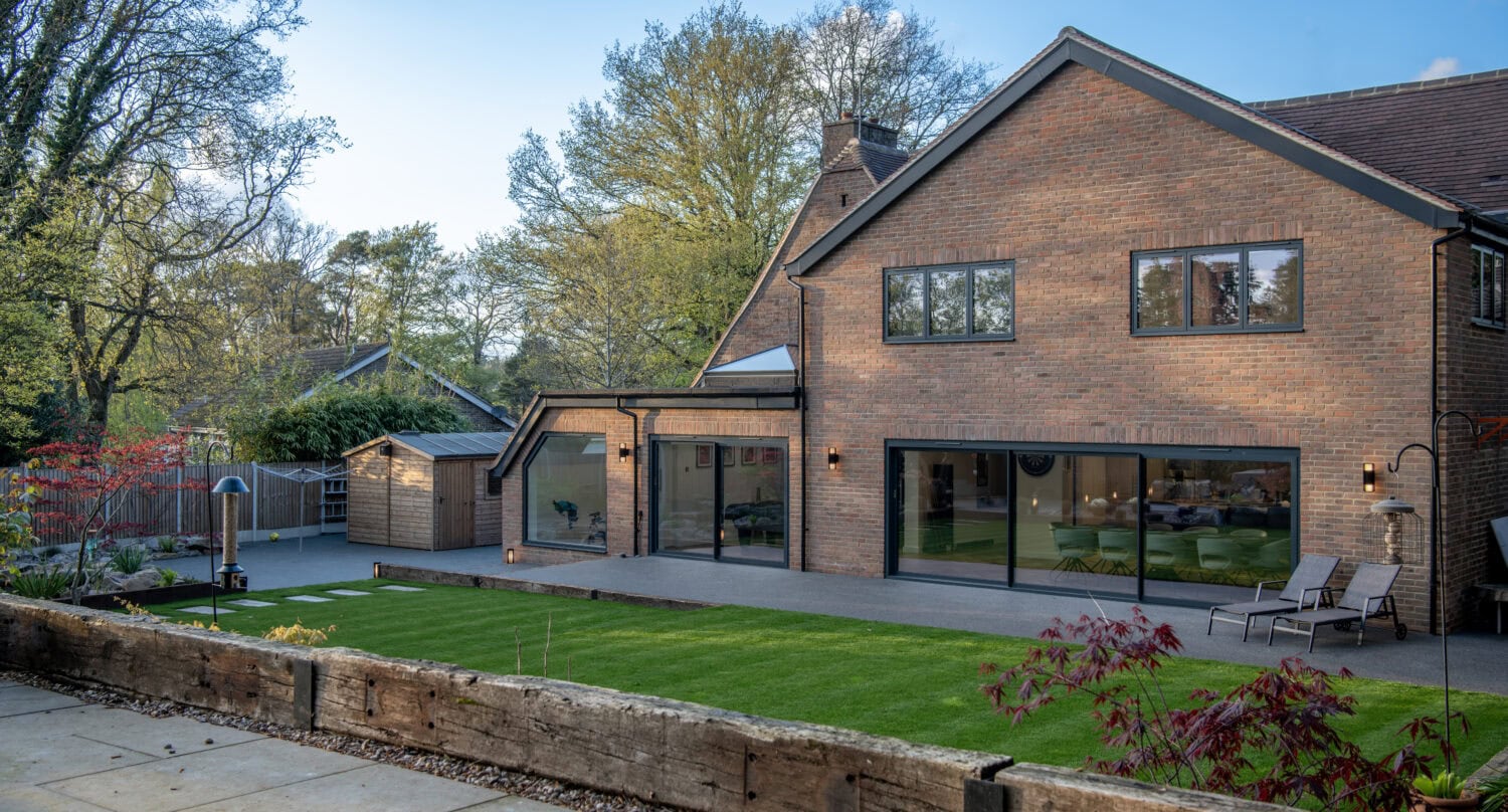 Beautiful brick house featuring large bi-folding doors opening to a landscaped garden, ideal for enhancing indoor-outdoor living spaces with stylish, energy-efficient bi-fold doors.