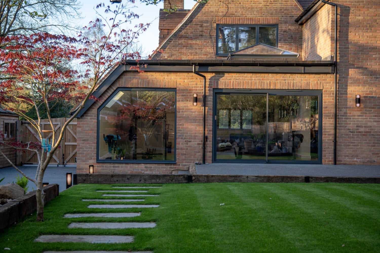 Black bi-folding doors opening to a garden, providing seamless indoor-outdoor living space. Perfect for enhancing natural light and aesthetic appeal in residential properties.