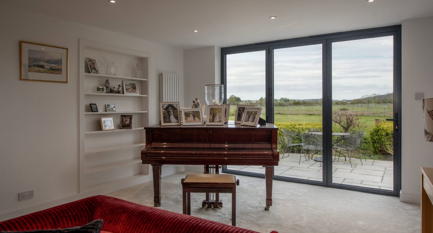 Bright living room featuring large bi-fold doors that open to a scenic garden, enhancing natural light and indoor-outdoor flow. Perfect for stylish, functional home design.