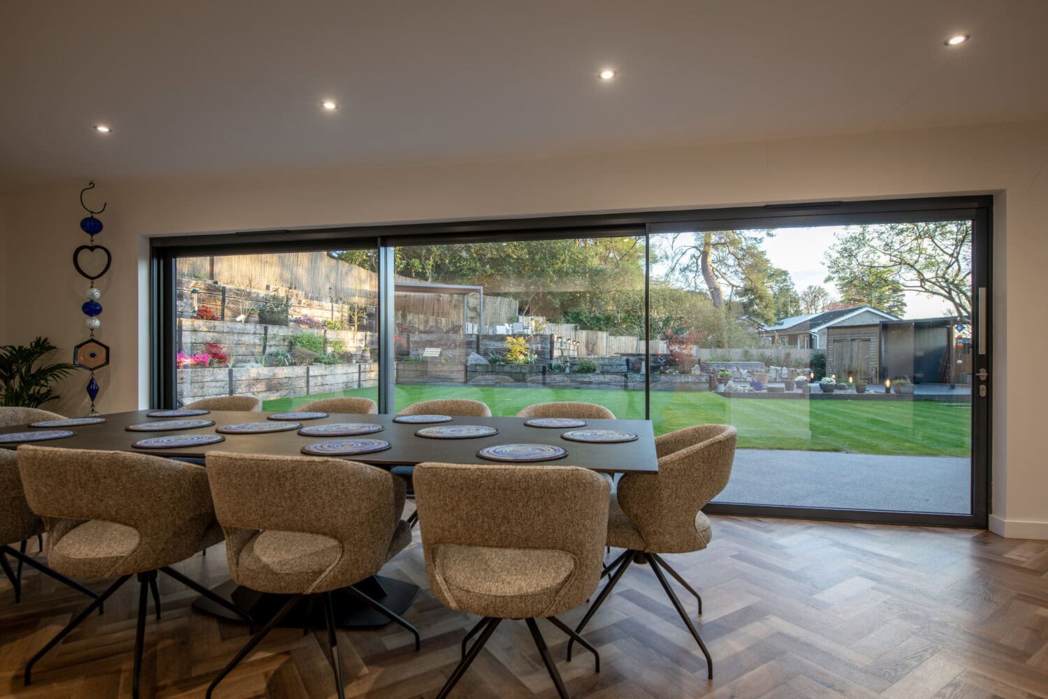 Spacious dining area featuring a large, sleek bi-fold door that opens to a lush garden, enhancing natural light and indoor-outdoor living. Perfect for contemporary homes seeking stylish, functional ac.