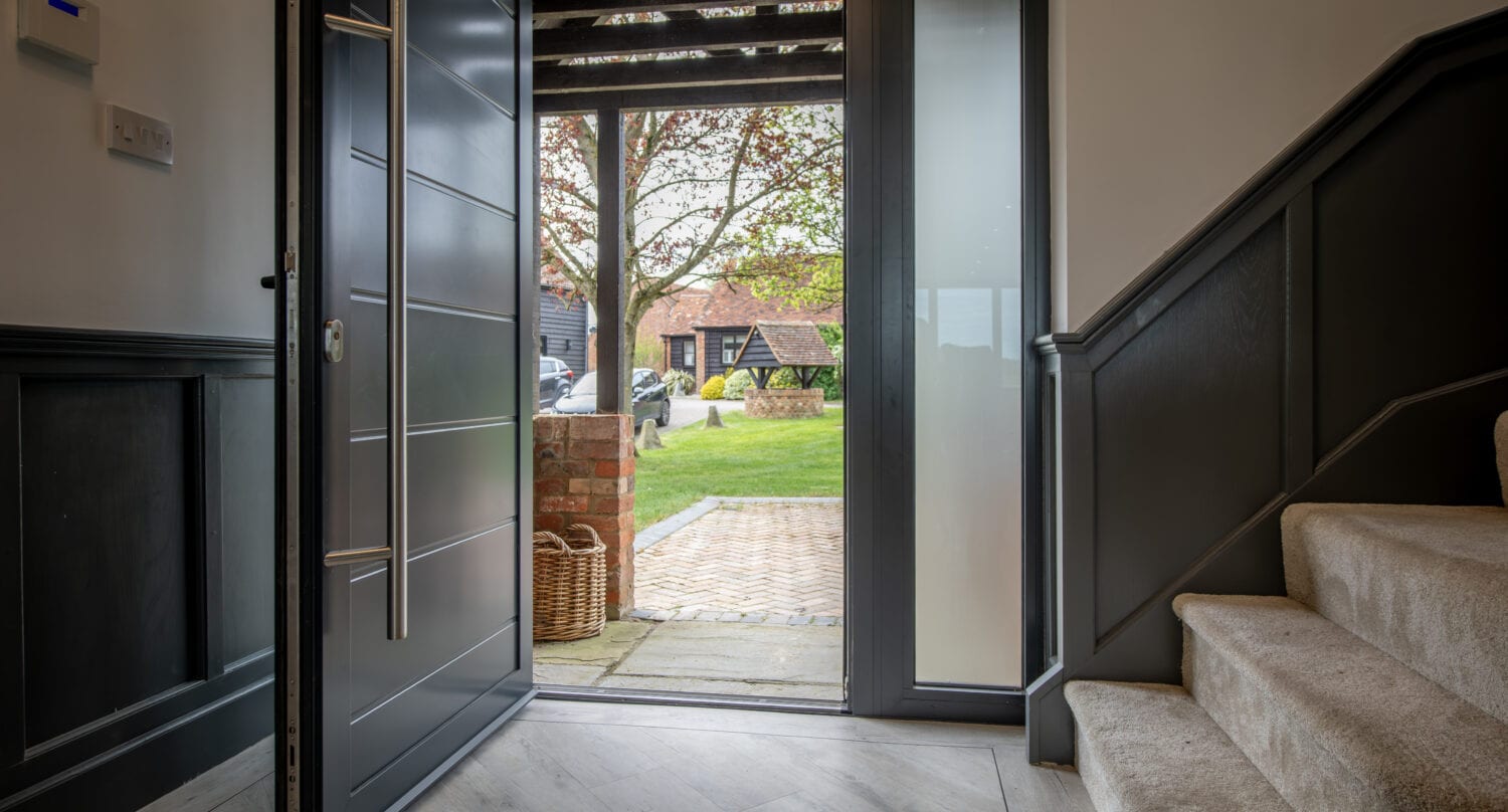 Black bi-folding doors opening to garden, showcasing stylish and functional home access. Perfect for enhancing indoor-outdoor living with sleek design and easy operation.