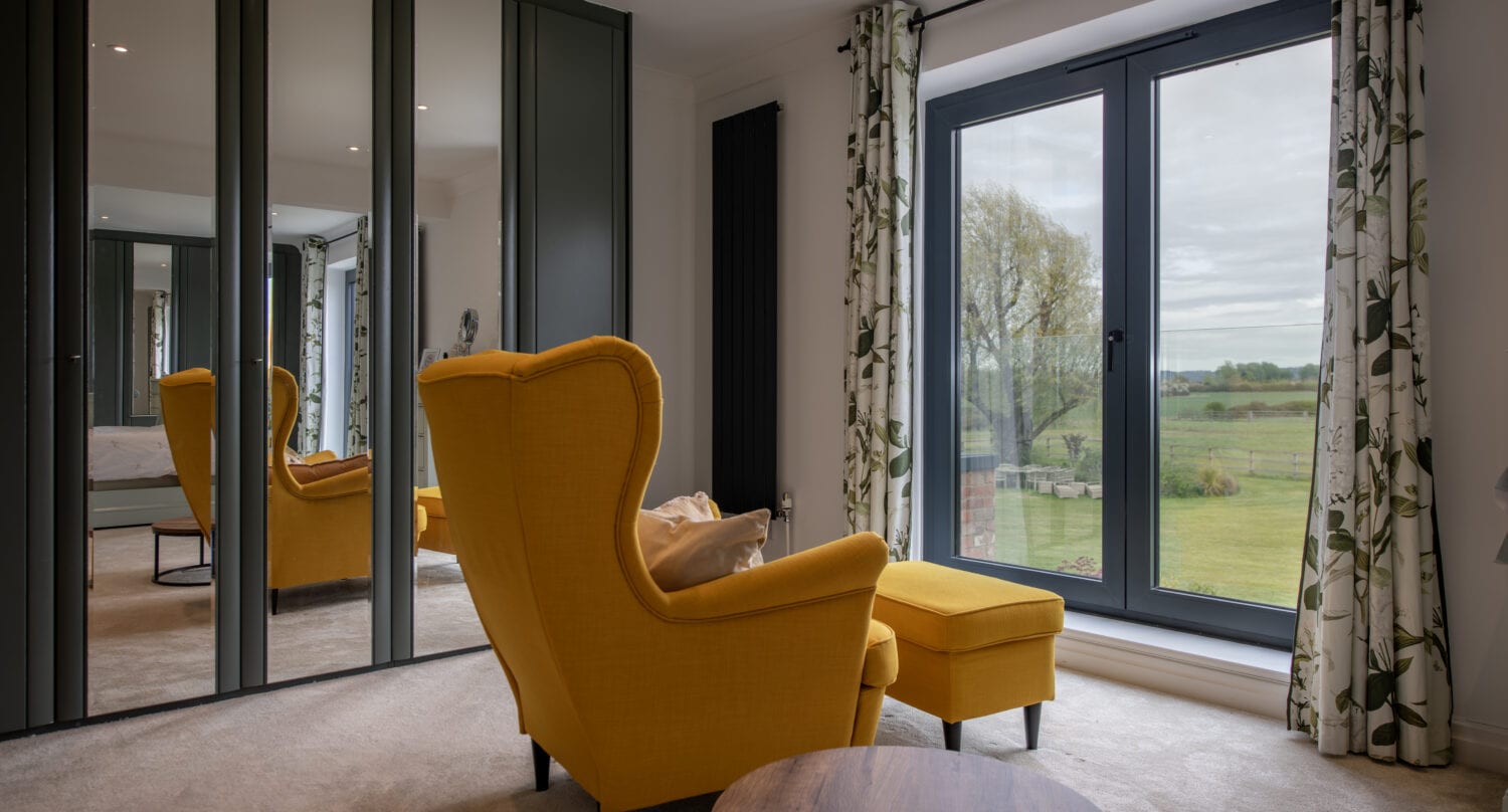 Elegant living room featuring large modern bi-fold doors that open to scenic outdoor views, enhancing natural light and indoor-outdoor living.