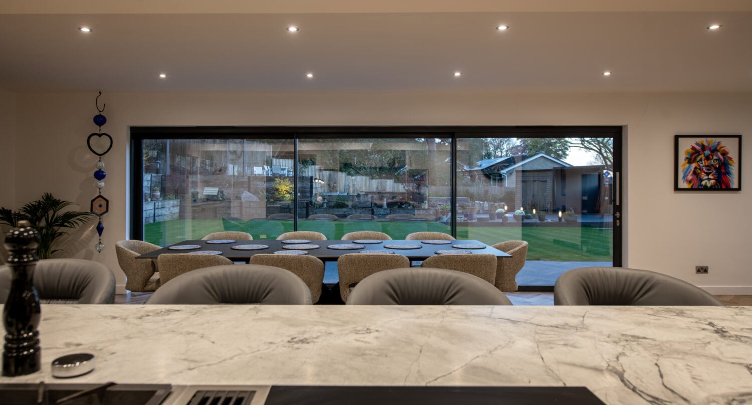Large glass sliding doors in a contemporary kitchen, offering a seamless transition between indoor and outdoor spaces, enhancing natural light and home aesthetics.