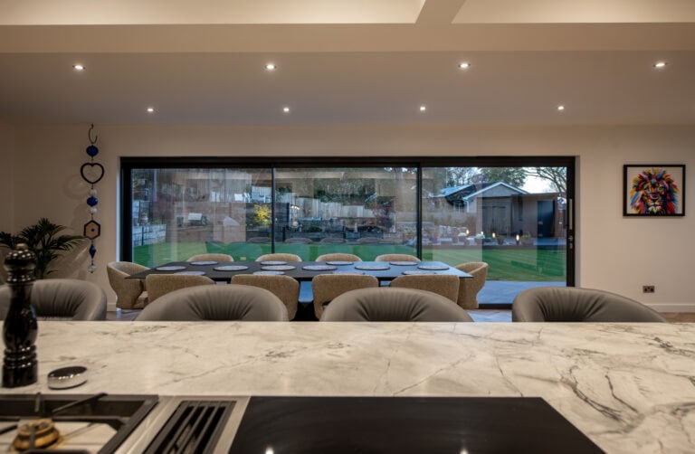 Large glass sliding doors in a contemporary kitchen, offering a seamless transition between indoor and outdoor spaces, enhancing natural light and home aesthetics.