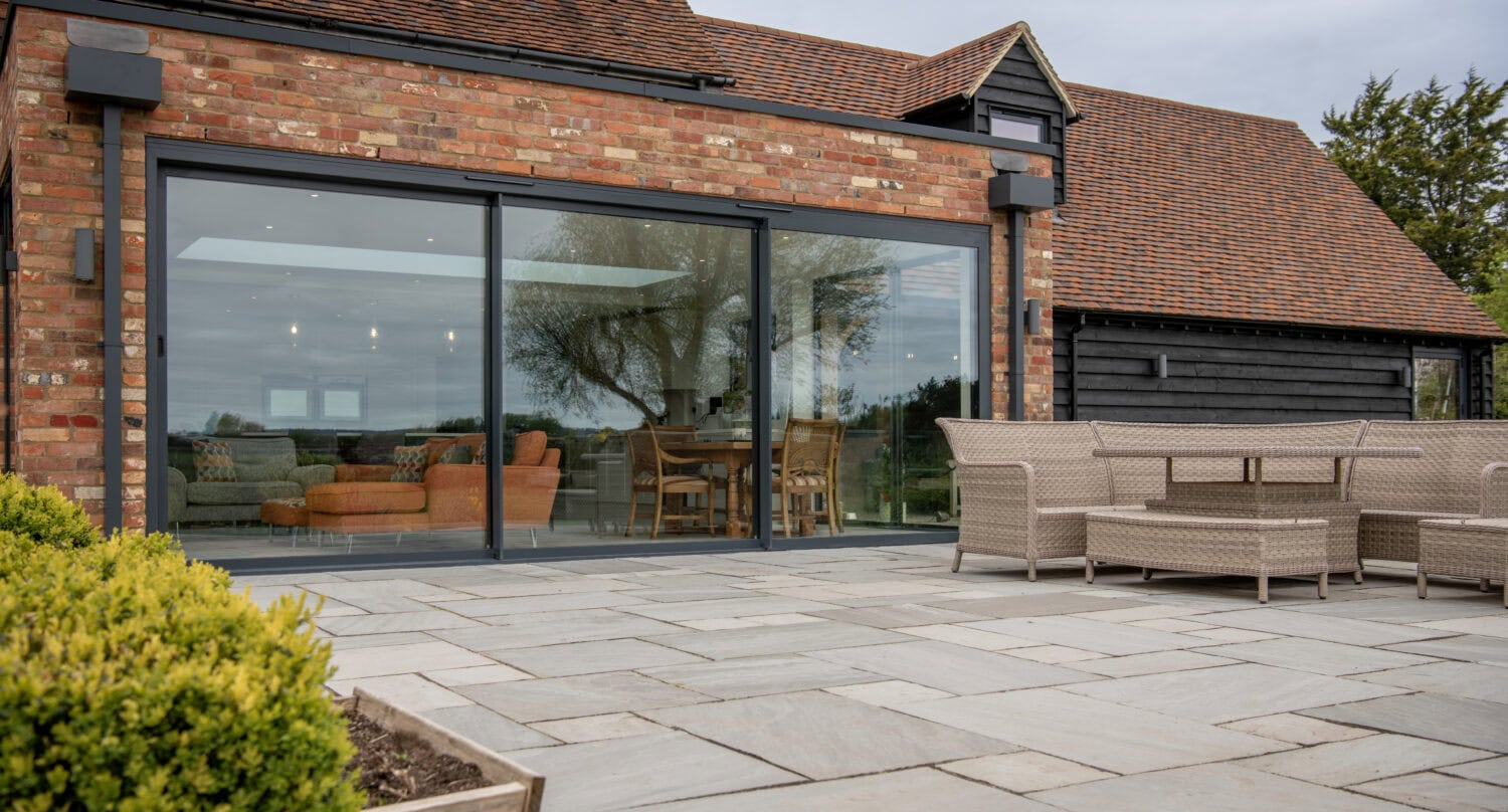 Elegant black bi-folding doors opening to a patio, enhancing indoor-outdoor living spaces with sleek design and functionality.