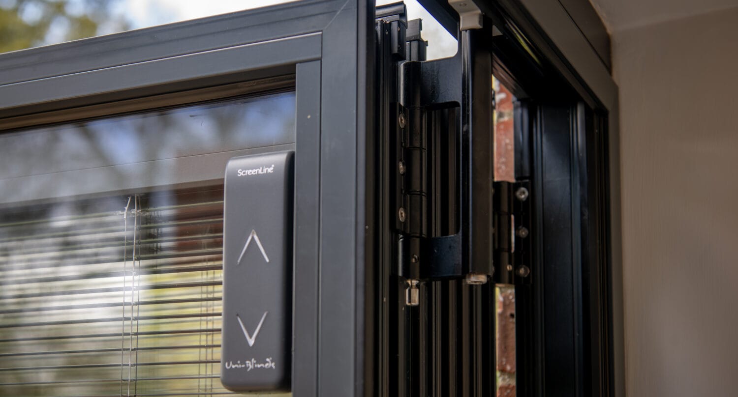 Close-up of a modern sliding bi-fold door with a focus on the sleek handle and track system, showcasing high-quality aluminium frames and smooth operation.