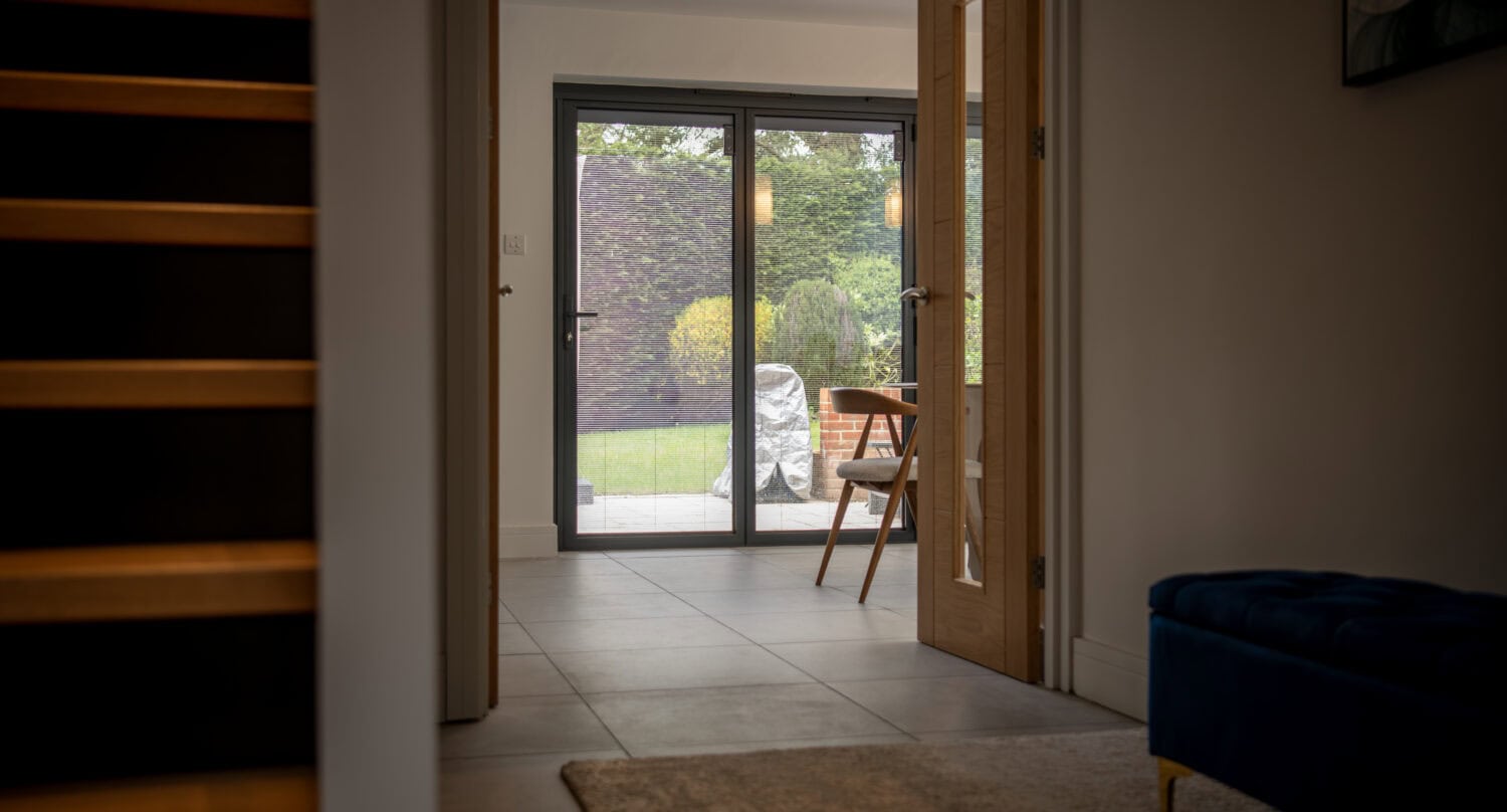 Elegant sliding bi-fold doors opening to a garden, providing seamless indoor-outdoor living space with natural light. Perfect for contemporary home designs.