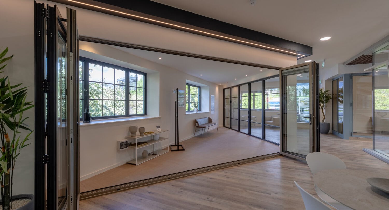 A wide view of a modern Milton Keynes showroom featuring large, energy-efficient bi-folding doors that open to an outdoor space, showcasing stylish and functional home improvement solutions.