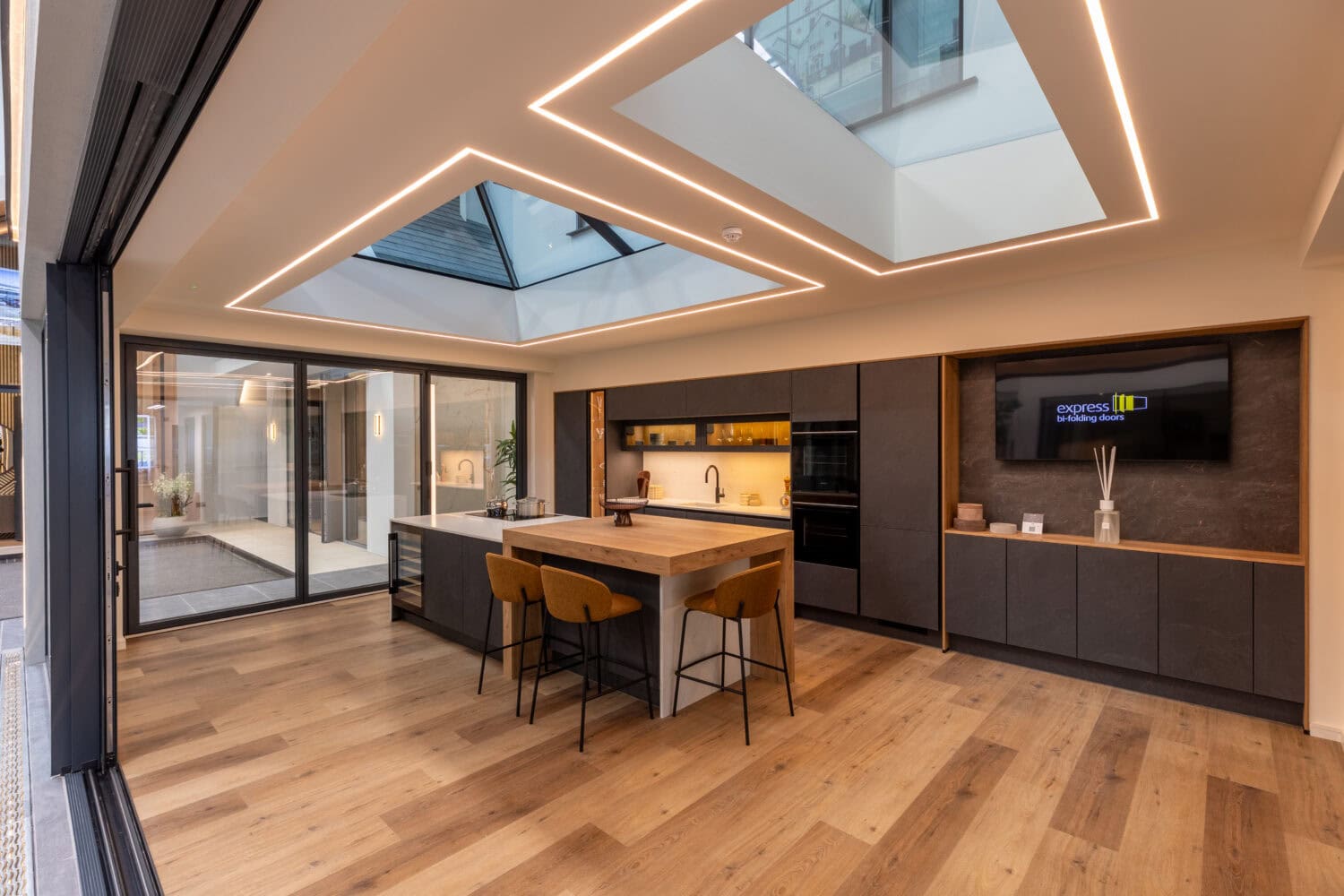 Elegant Milton Keynes showroom featuring modern bi-fold doors, sleek kitchen design, and innovative lighting, showcasing high-quality Express Bi-Folding Doors for stylish home transformations.