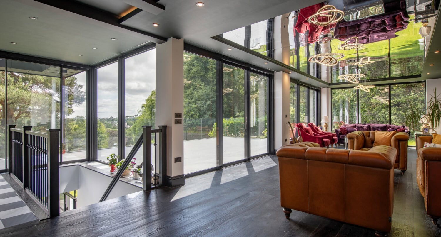 Modern interior with large glass bi-fold doors opening to outdoor greenery at Stumperlowe Hall.