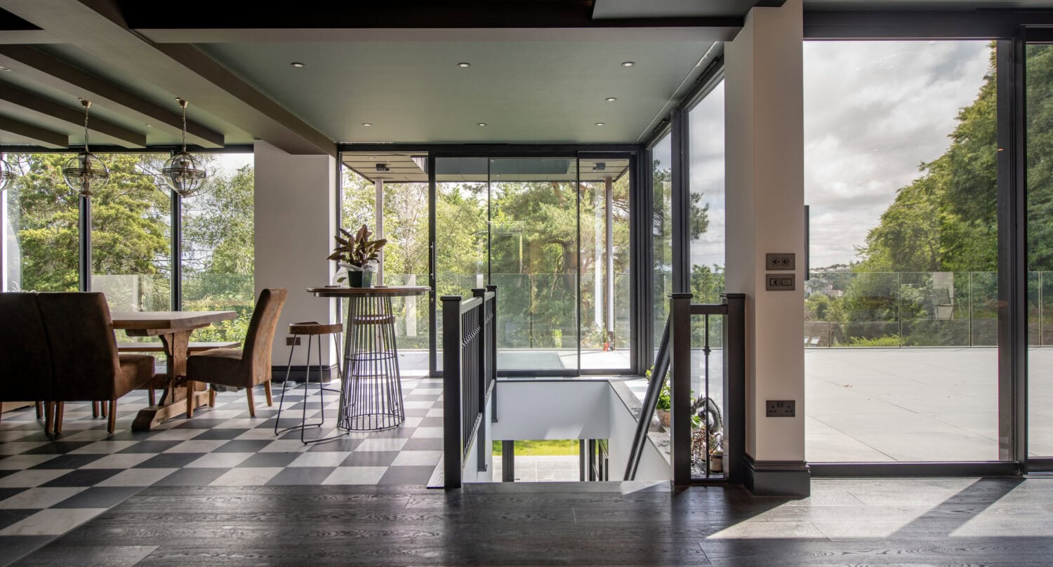 Modern interior with large glass bi-folding doors opening to outdoor greenery at Stumperlowe Hall, showcasing stylish design and natural light.