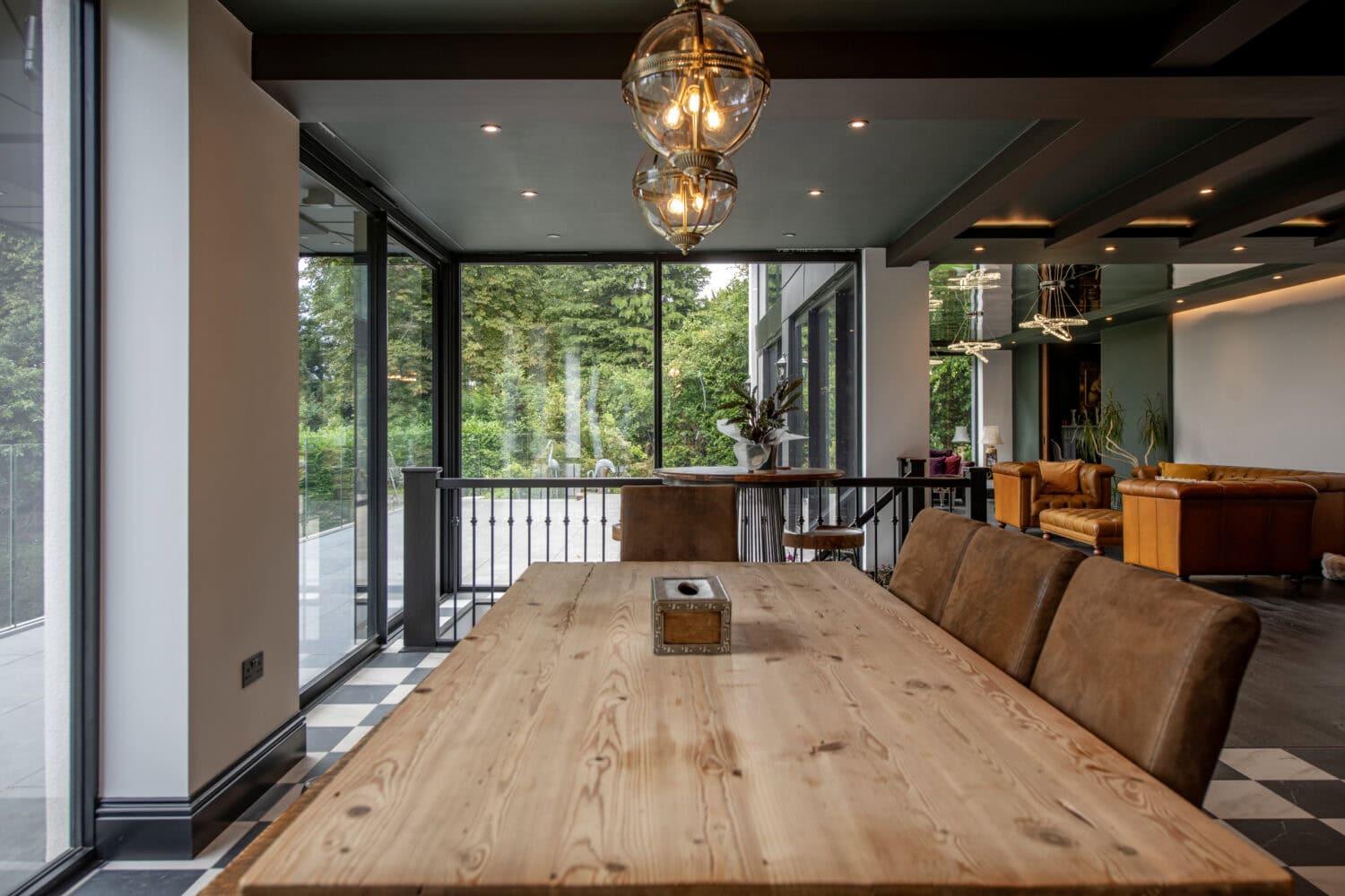 Modern interior with large glass bi-fold doors opening to a lush green garden, showcasing stylish design and natural light at Stumperlowe Hall.
