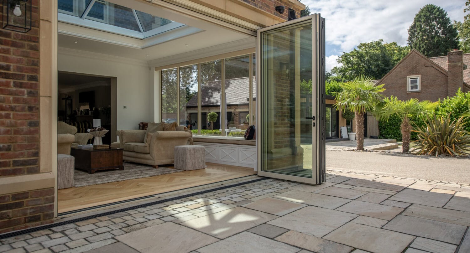 Modern bi-fold doors opening to a patio with garden views at Foxwood House, showcasing seamless indoor-outdoor living.