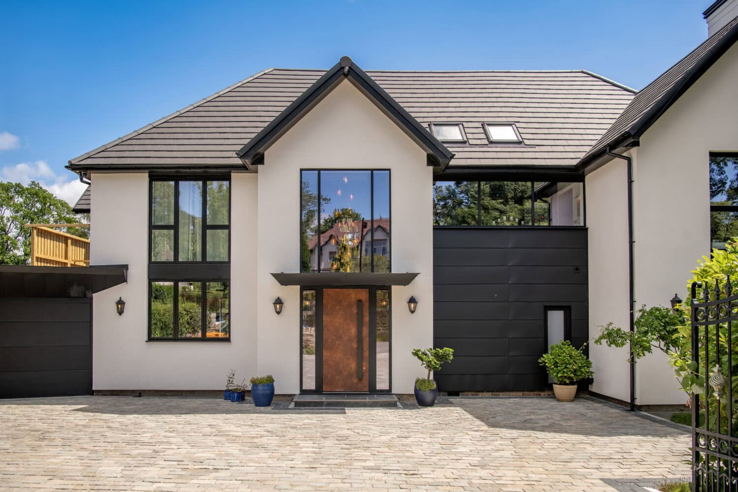 Modern house featuring large black bi-folding doors and expansive windows, showcasing stylish and functional home design.