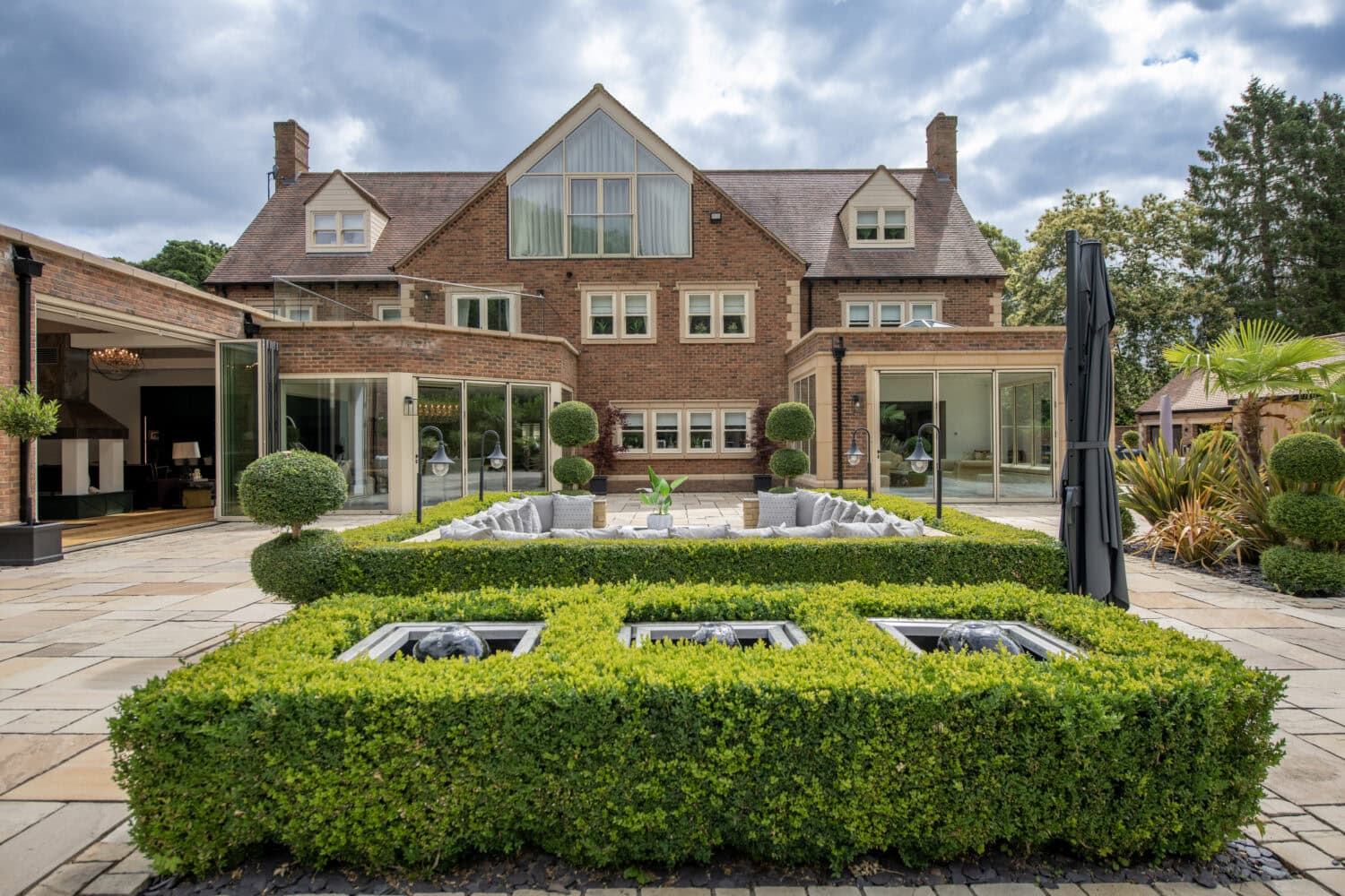 Elegant house with large bi-folding doors opening to a landscaped garden and patio area, showcasing modern outdoor living space.
