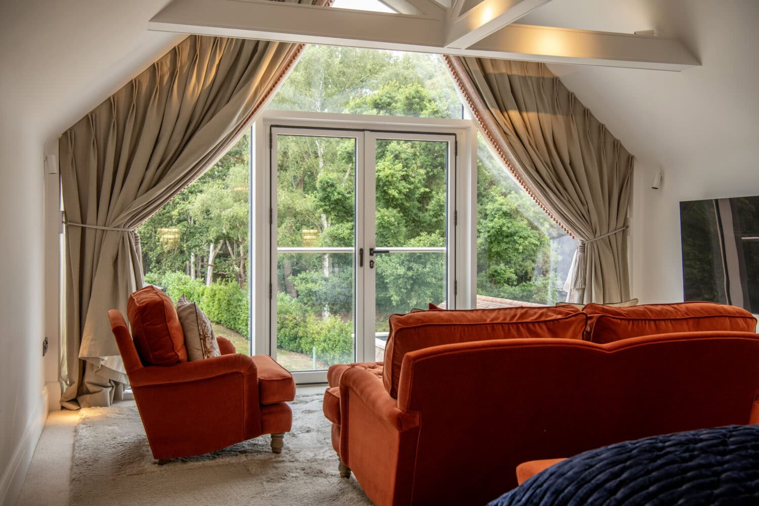Elegant living room with large glass bi-folding doors opening to a garden, showcasing stylish interior design and natural light.
