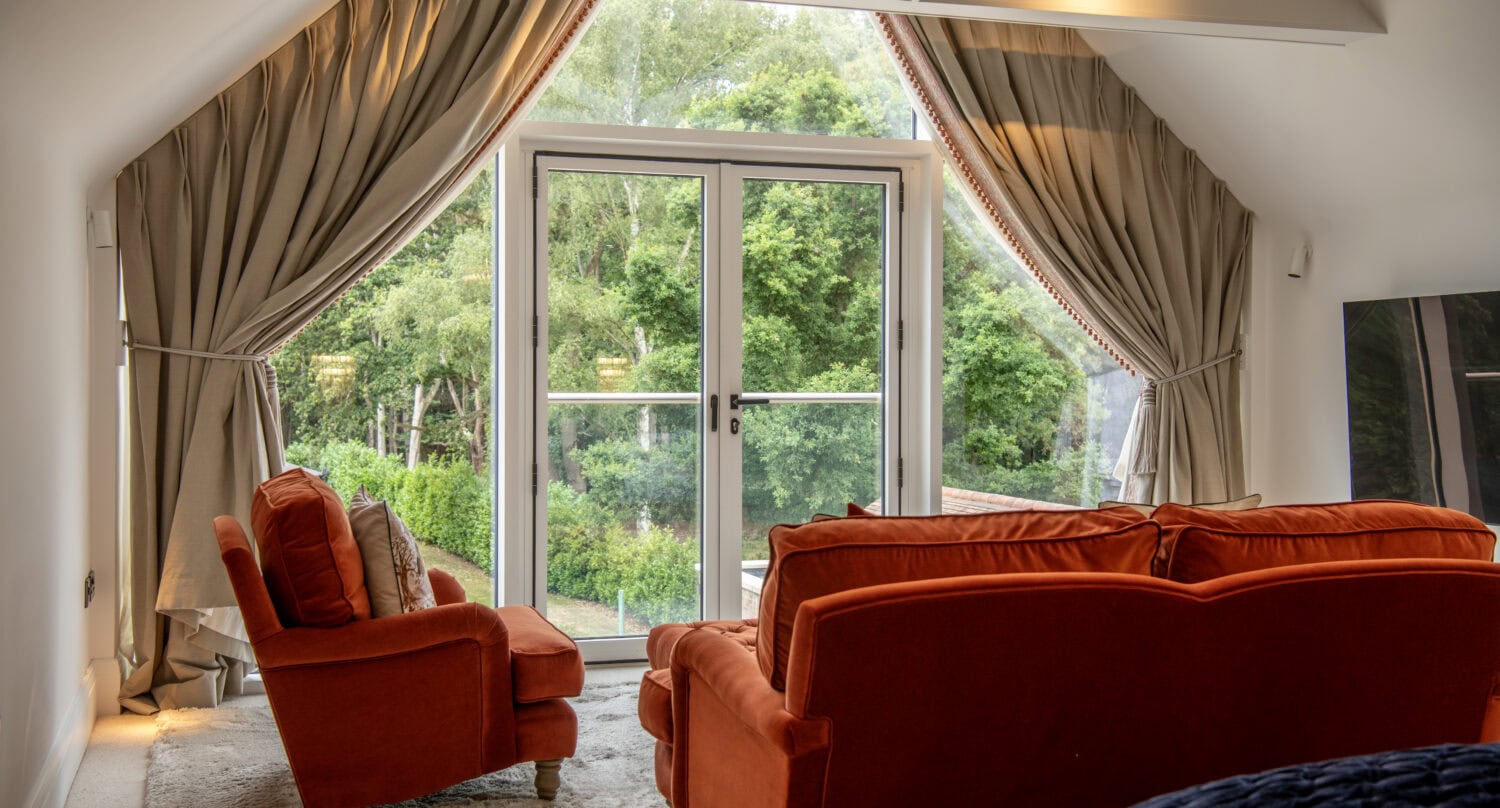 Elegant living room with large glass bi-folding doors opening to a garden, showcasing stylish interior design and natural light.