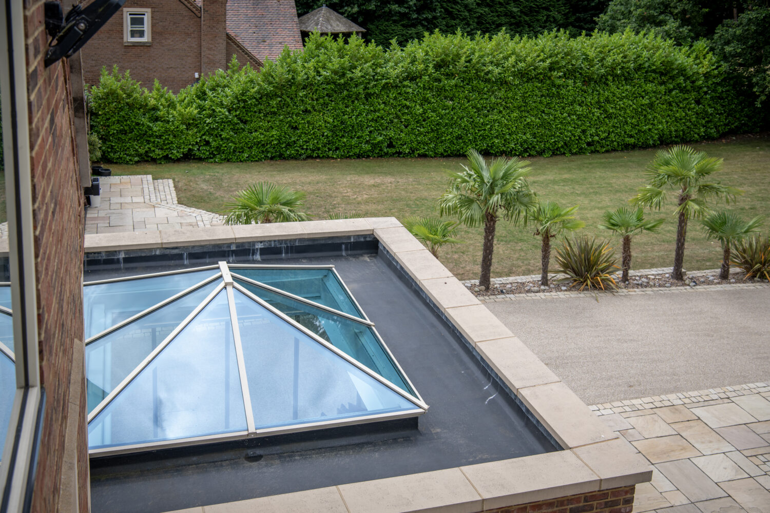 Modern bi-folding doors opening to a landscaped garden with a swimming pool and lush greenery, showcasing stylish outdoor living.