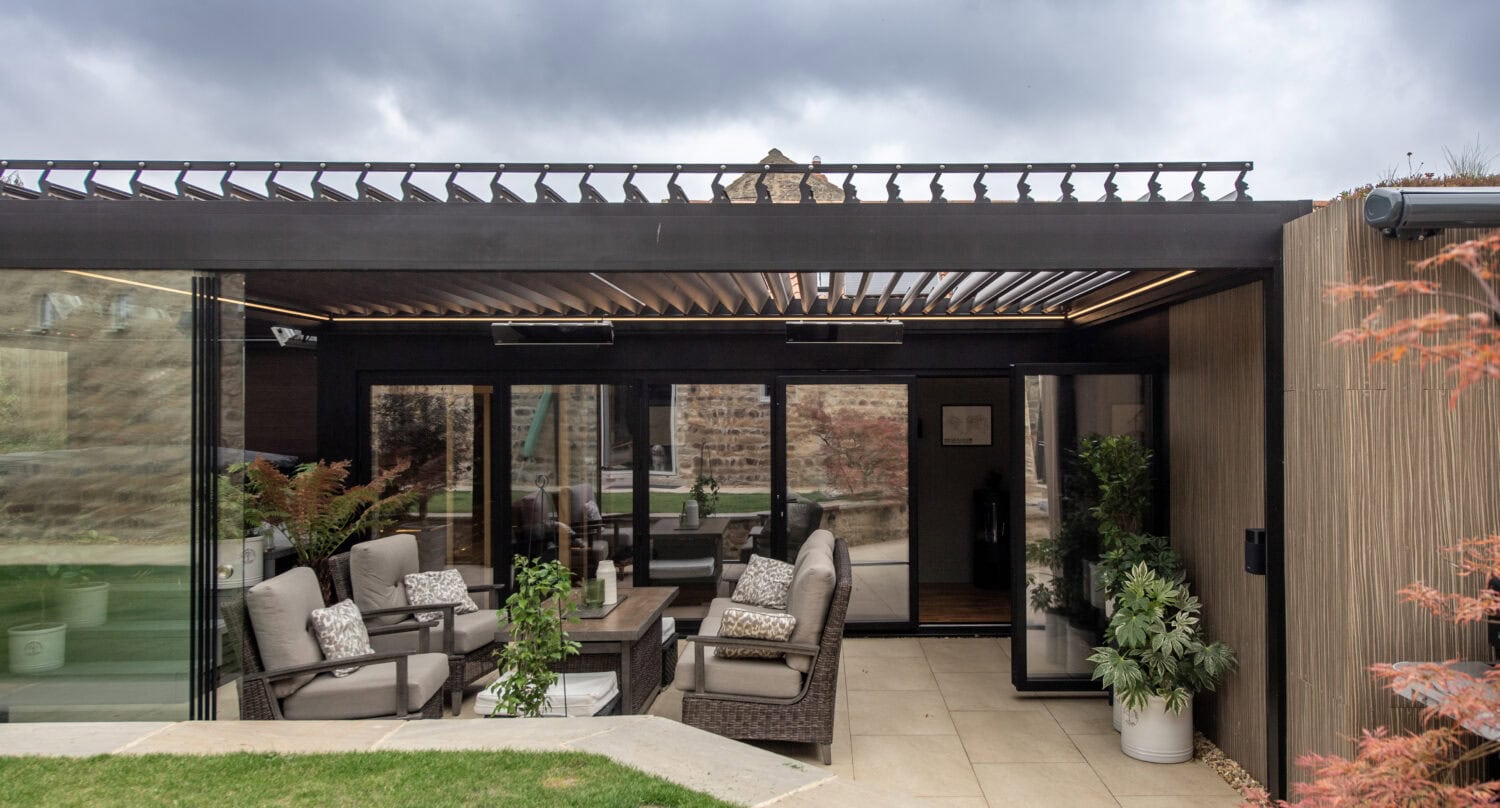 Contemporary outdoor space with large bi-folding doors opening to a garden patio, featuring comfortable seating and modern design elements.