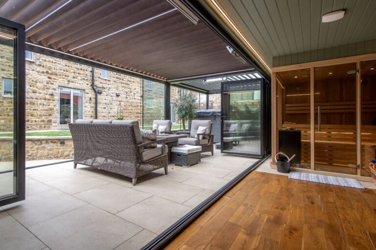 Contemporary garden room featuring large bi-folding doors opening to outdoor seating area, ideal for indoor-outdoor living and entertaining.