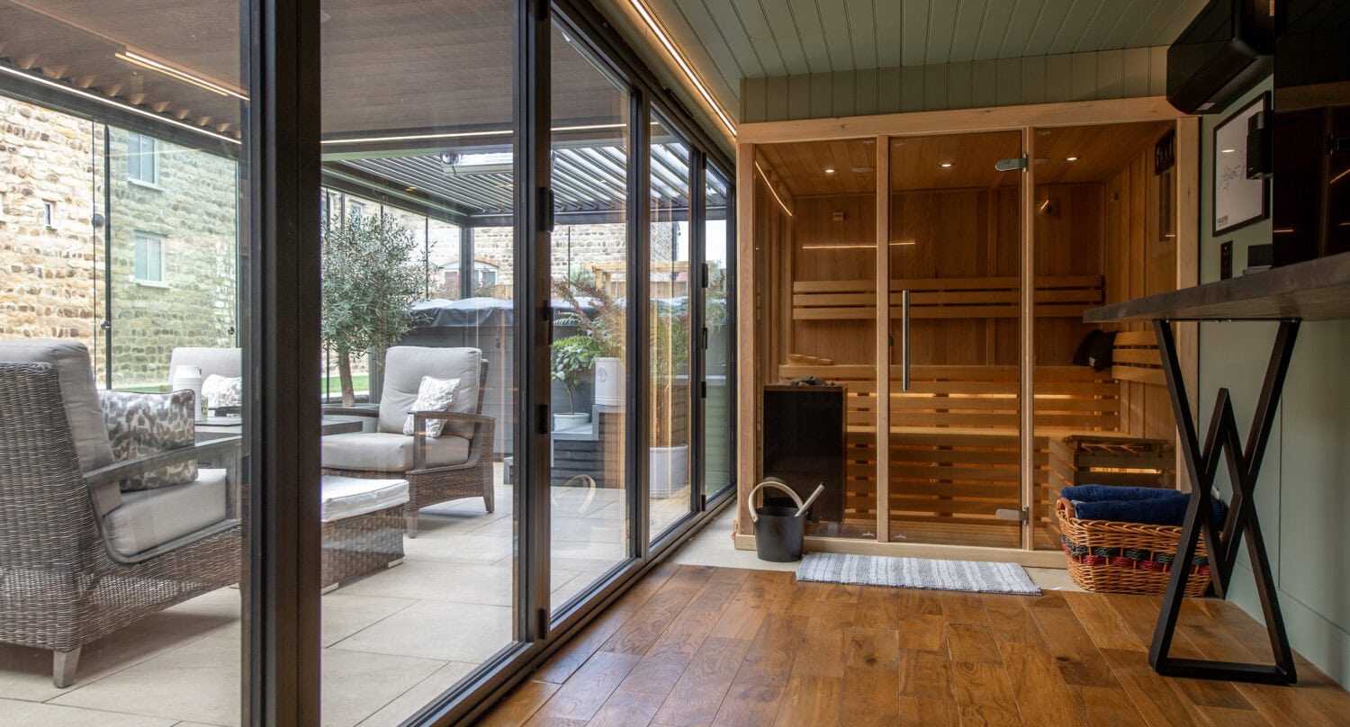 Modern home with large glass bi-folding doors opening to outdoor patio and garden, showcasing seamless indoor-outdoor living space.