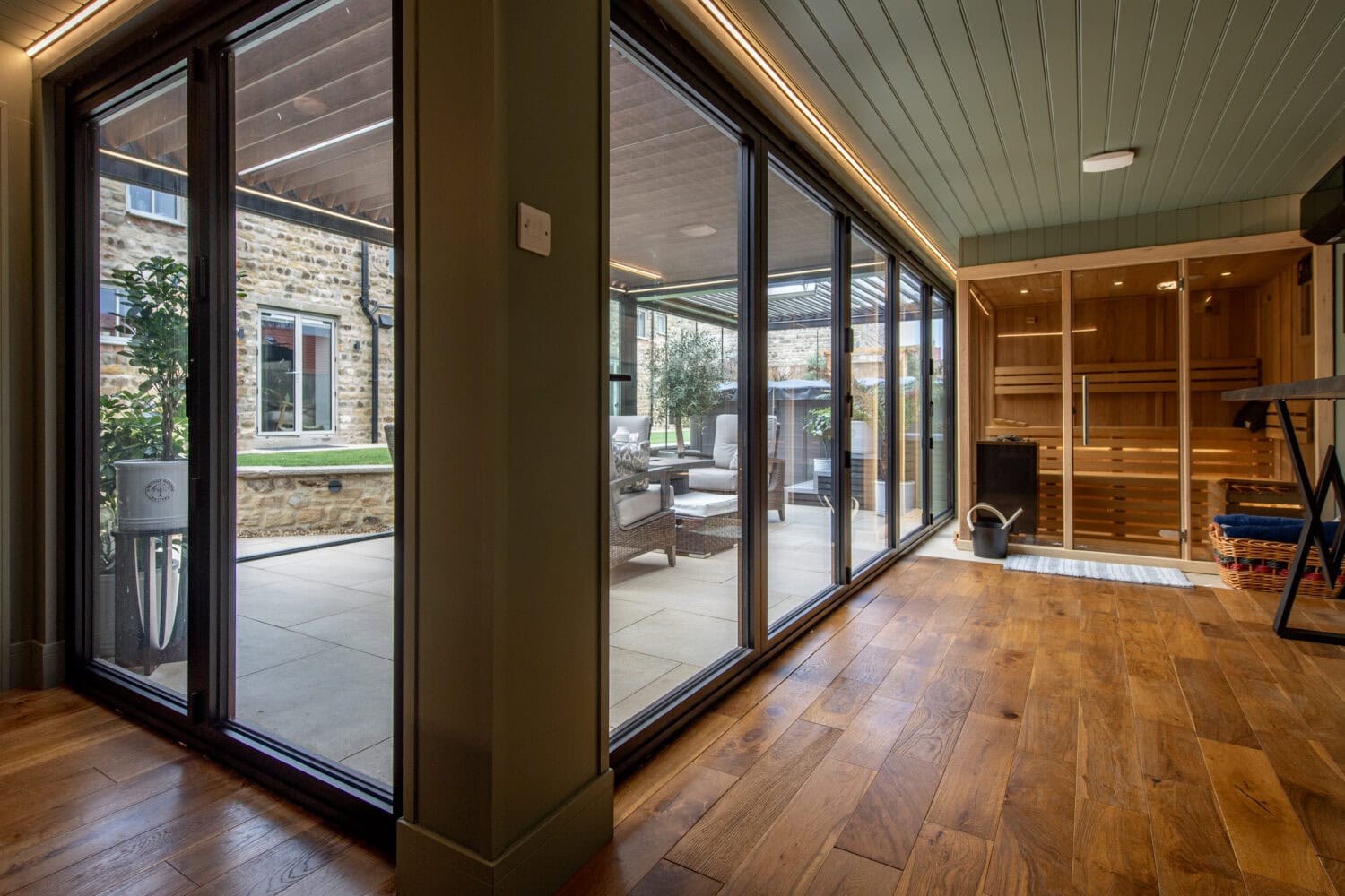 Elegant black bi-folding doors opening to a garden patio, enhancing indoor-outdoor living space with large glass panels and sleek design.
