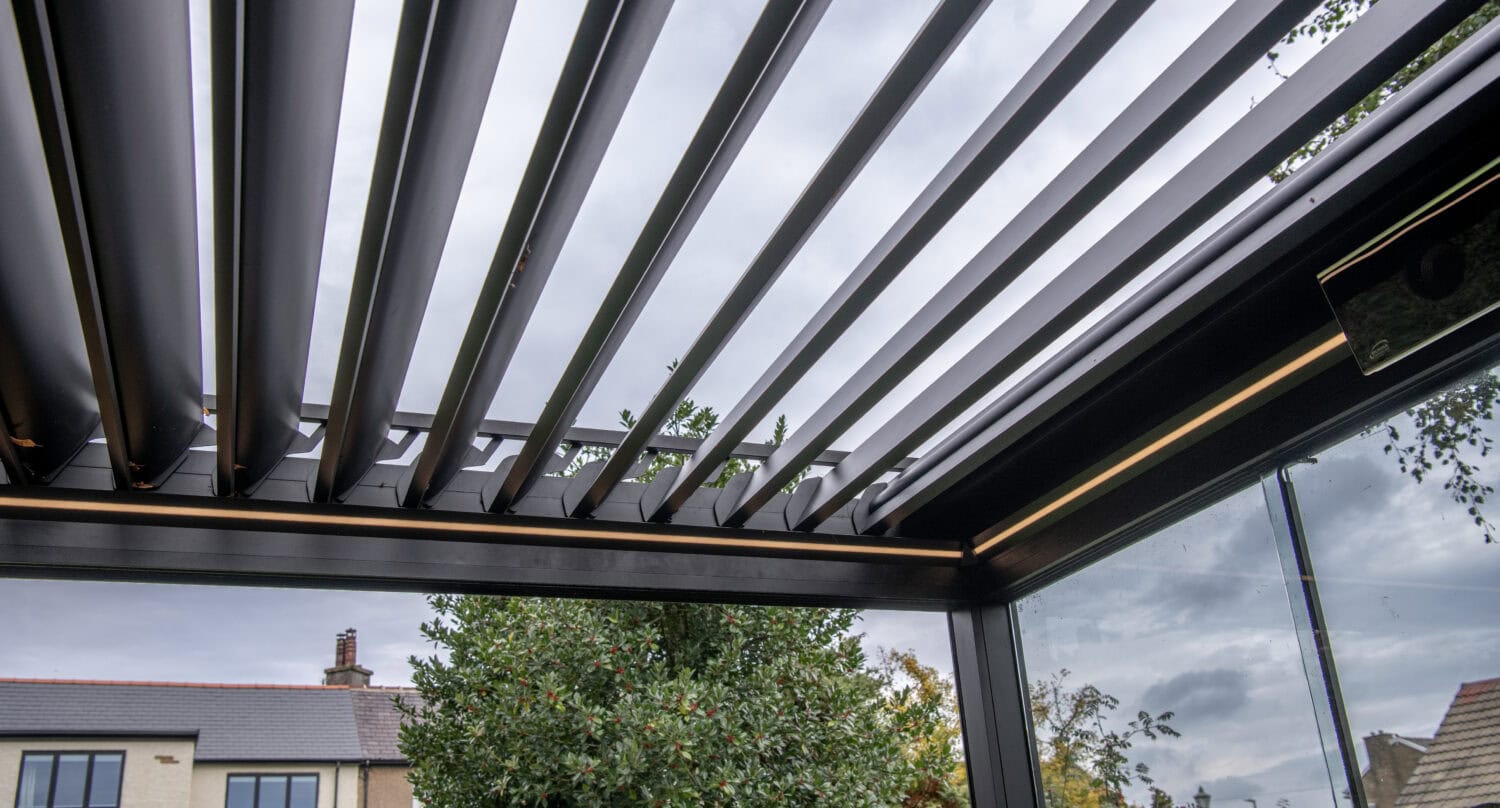 Modern outdoor living space featuring Express Bi-Folding Doors with integrated solar shading and louvered roof for enhanced outdoor comfort.
