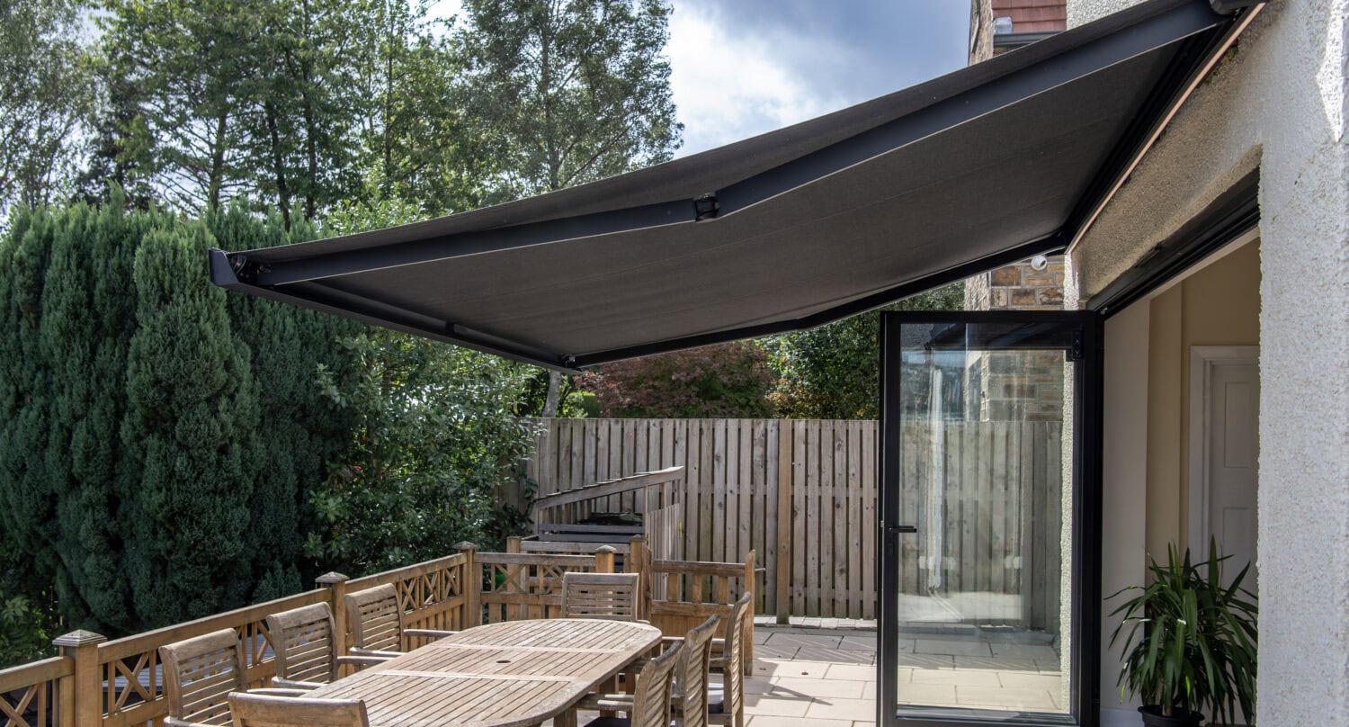 Modern outdoor living space featuring bi-folding doors and a large retractable sunshade, ideal for outdoor dining and relaxation.