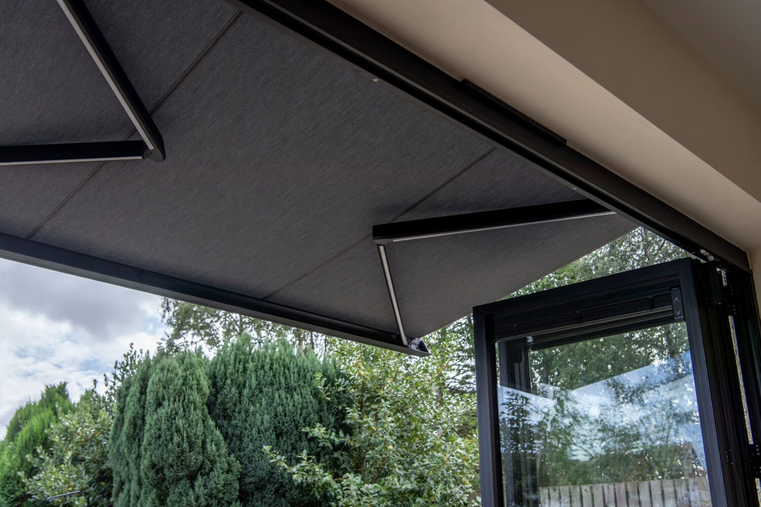 Modern outdoor living space featuring Express Bi-Folding Doors and a retractable sunshade, ideal for outdoor shading and seamless indoor-outdoor connection.